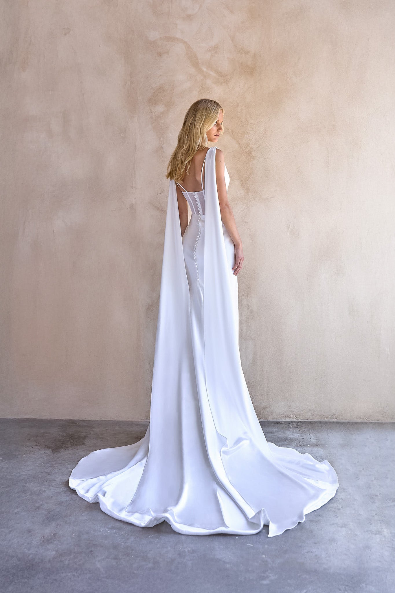 Full back image of Jani satin wedding dress by the bryde. exposed boning bodice with illusion tulle back and button detail.
