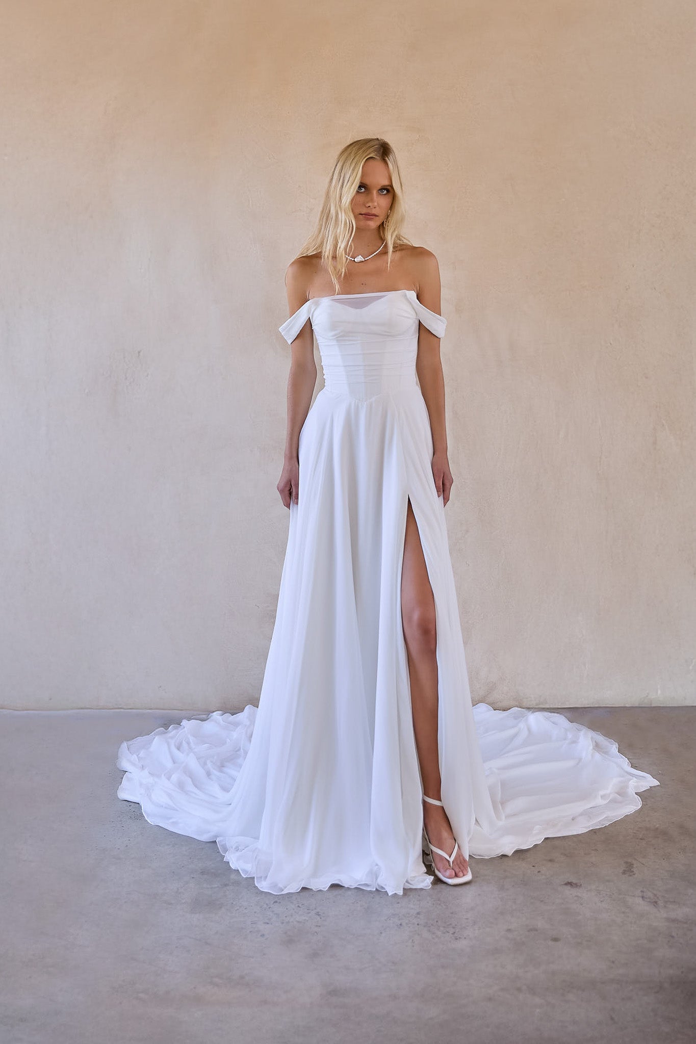 jessi is an off shoulder chiffon a-line wedding dress with thigh high split. ruched chiffon bodice with v waist design to enhance silhouette