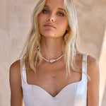 Dramatic sweetheart neckline of The Bryde's Jaya bridal dress styled with pearl necklace and cluster pearl bridal earrings